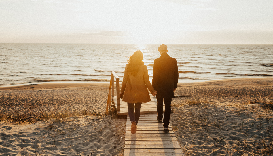 Una pareja agarrados de la mano caminando por la orilla del mar