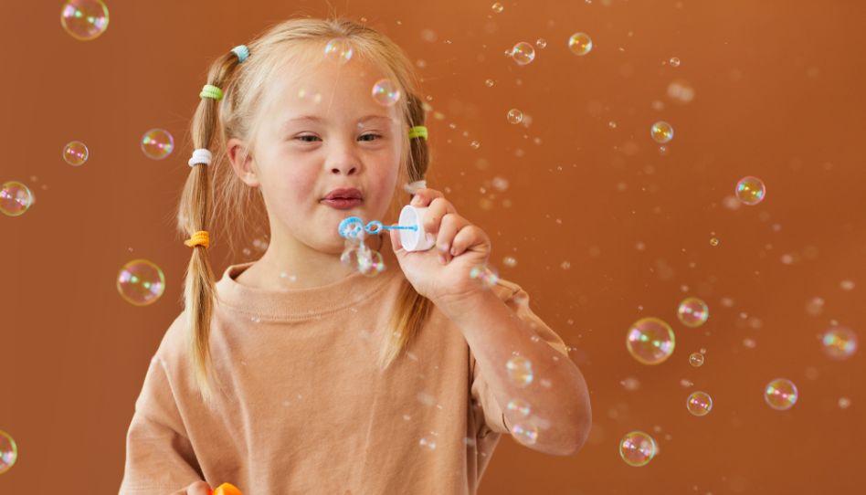 una niña con síndrome de Down soplando burbujas